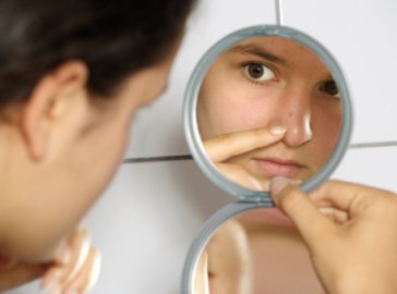 Foto von junger Frau beim Blick in den Spiegel